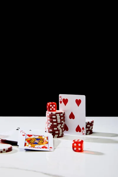 Jetons de casino, dés et cartes à jouer sur une surface blanche isolée sur noir — Photo de stock