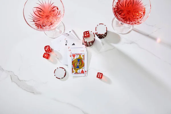 High angle view of playing cards, glasses of cocktail, dice and casino chips on white background — Stock Photo