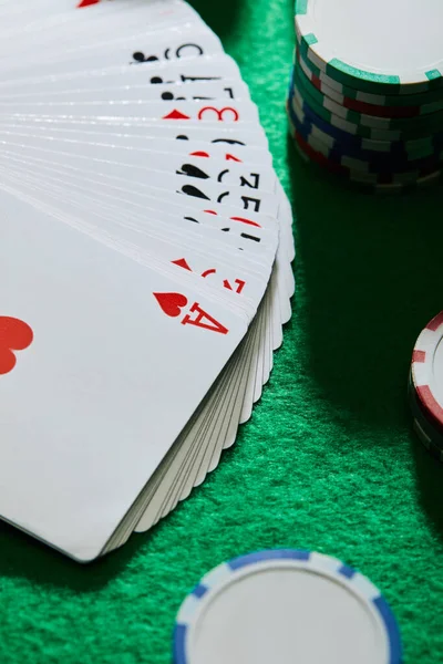 Vista de ángulo alto de jugar a las cartas con fichas de casino en verde - foto de stock