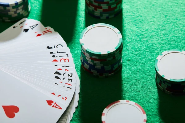 High angle view of playing cards with casino chips on green background — Stock Photo