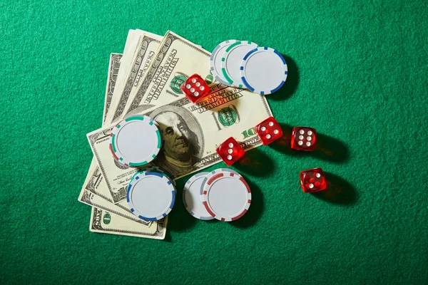 Top view of dollar banknotes, dice and casino chips on green — Stock Photo