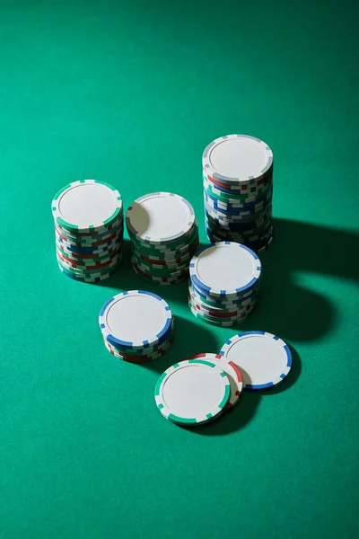 Vista de ángulo alto de fichas de casino sobre fondo verde - foto de stock