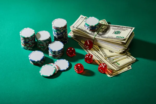 Vue à angle élevé des billets en dollars, des dés et des jetons de casino sur vert — Photo de stock