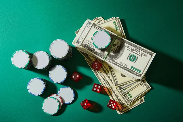 Top view of dollar banknotes, dice and casino tokens on green background — Stock Photo