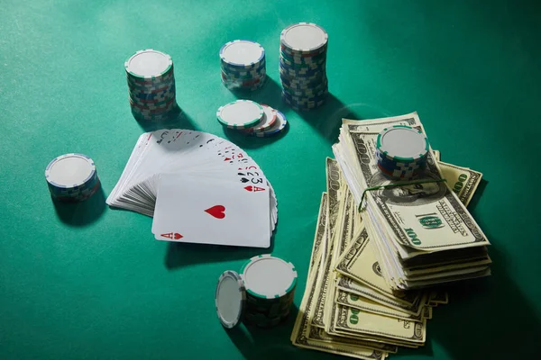 High angle view of playing cards, casino tokens and dollar banknotes on green background — Stock Photo