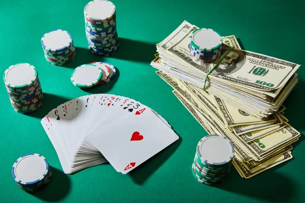 High angle view of playing cards, casino tokens and dollar banknotes on green — Stock Photo