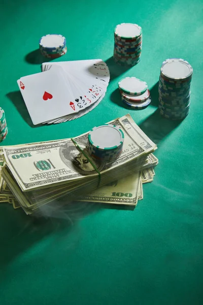 High angle view of playing cards, casino chips and dollar banknotes on green — Stock Photo