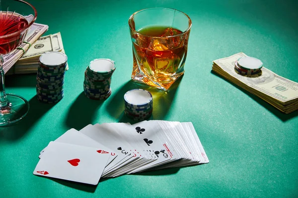 Hochwinkelblick auf Cognacgläser und Cocktails mit Geld, Casino-Chips und Spielkarten auf Grün — Stockfoto