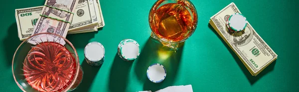 Vista dall'alto di occhiali di cognac e cocktail con soldi e patatine di casino su colpo verde, panoramico — Foto stock