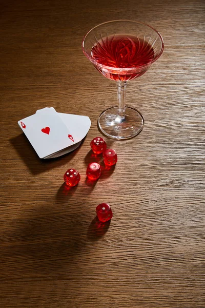 Vue grand angle du verre de cocktail près du jeu de cartes et dés sur fond en bois — Photo de stock