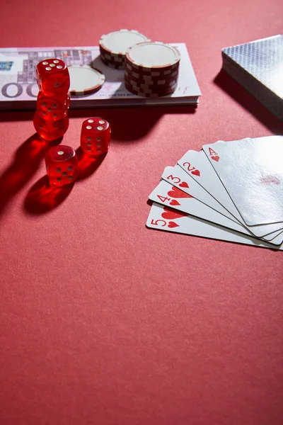 High angle view of playing cards, dice, casino chips and money on red — Stock Photo