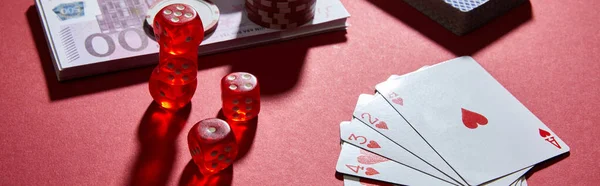 High angle view of playing cards, dice and money on red, panoramic shot — Stock Photo