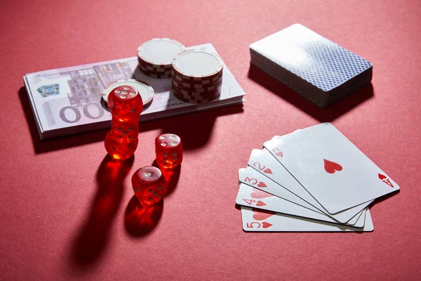 Vista ad alto angolo di carte da gioco, dadi, fiches da casinò e banconote in rosso — Foto stock