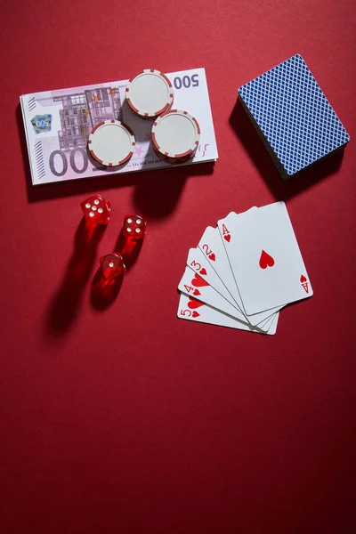 Vue du dessus des cartes à jouer, dés, jetons de casino et billets de banque sur rouge — Photo de stock