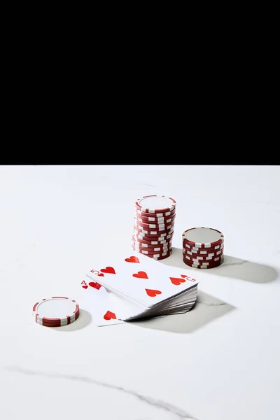 High angle view of casino chips near deck of cards on white surface isolated on black — Stock Photo