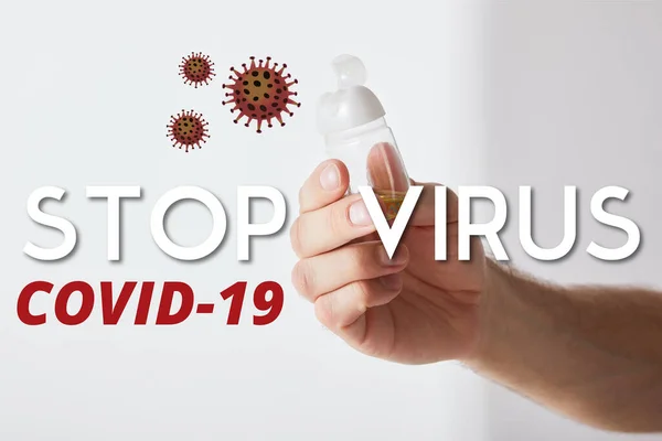 Cropped view of man holding hand sanitizer on grey background, stop virus illustration — Stock Photo