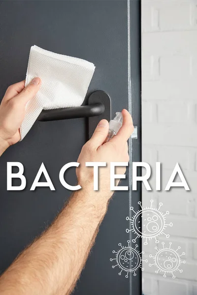 Vue partielle de l'homme désinfectant poignée de porte en métal avec antiseptique et serviette, illustration de bactéries — Photo de stock
