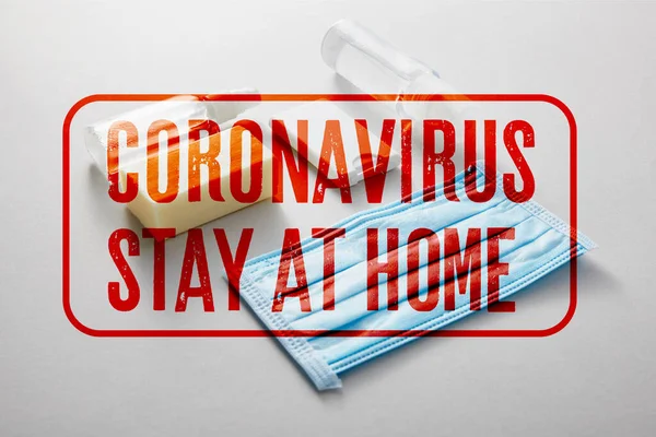 Posa piatta con disinfettante per le mani in flaconi spray, maschera medica e sapone antibatterico su sfondo grigio, coronavirus rimanere a casa illustrazione — Foto stock