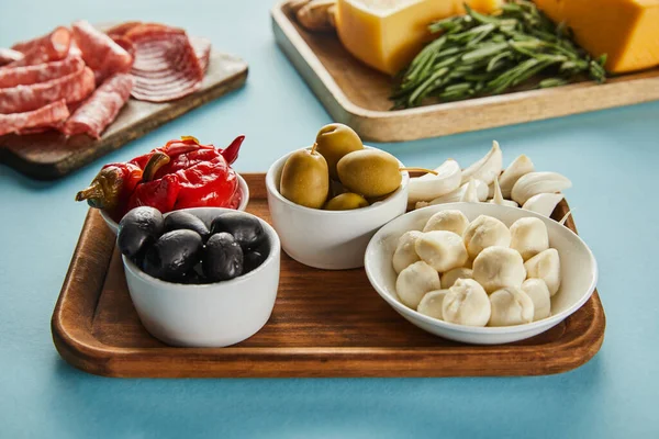 Foco seletivo de ingredientes antipasto em placas no fundo azul — Fotografia de Stock