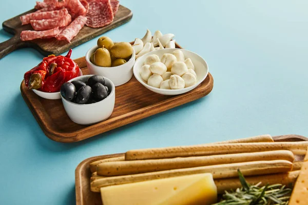 Vista de ángulo alto de los ingredientes antipasto en las tablas en azul - foto de stock