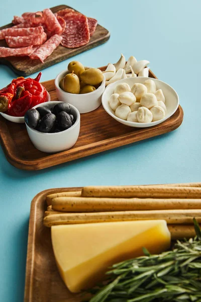 Visão de alto ângulo de ingredientes antipasto em placas no fundo azul — Fotografia de Stock