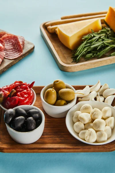 Vista en ángulo alto de tableros con ingredientes antipasto sobre fondo azul — Stock Photo