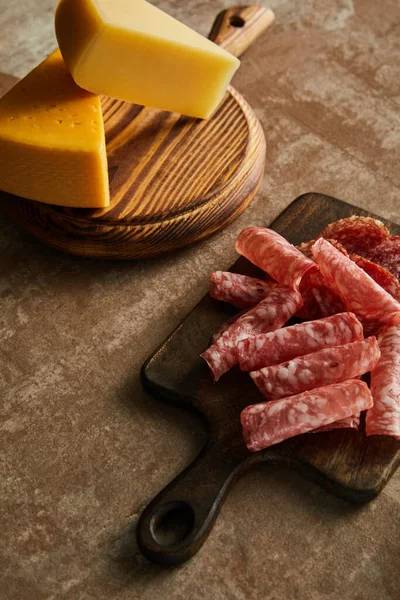 High angle view of boards with salami slices and cheese on brown — Stock Photo