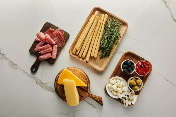 Acostado plano con ingredientes antipasto en tablas sobre blanco - foto de stock