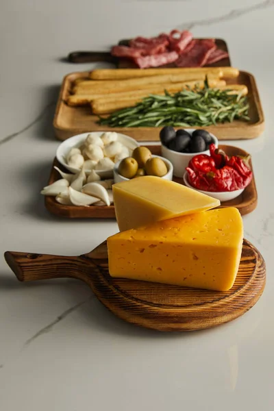 Foco seletivo de placas com queijo e ingredientes antipasto no fundo branco — Fotografia de Stock