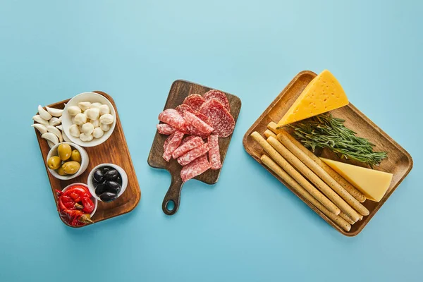 Top view of antipasto ingredients on boards on blue background — Stock Photo