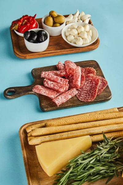 High angle view of antipasto ingredients on boards on blue background — Stock Photo