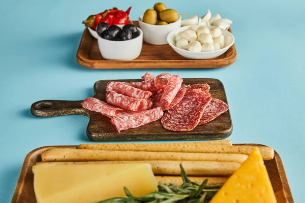 Enfoque selectivo de ingredientes antipasto en tableros sobre fondo azul - foto de stock