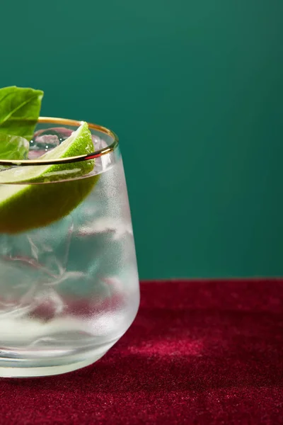 Nahaufnahme von geschnittenem Glas mit erfrischendem Mojito, Minze und Limettenscheibe isoliert auf Grün — Stockfoto