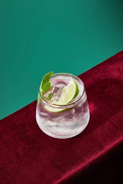 Vue grand angle du verre avec mojito frais, menthe et tranche de lime sur fond vert et noir — Photo de stock