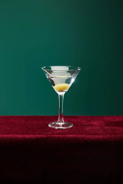 Crystal cocktail glass with vermouth and whole olive on toothpick isolated on green — Stock Photo