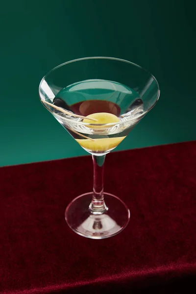 Vue grand angle du verre à cocktail en cristal avec vermouth et olive entière sur cure-dent isolé sur vert — Photo de stock