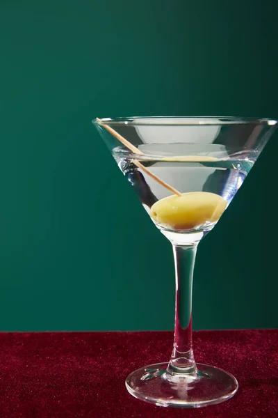Close up view of cocktail glass with vermouth and whole olive on toothpick isolated on green — Stock Photo