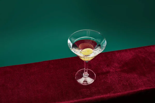 Vue grand angle du verre à cocktail avec vermouth et olive entière sur cure-dent isolé sur vert — Photo de stock