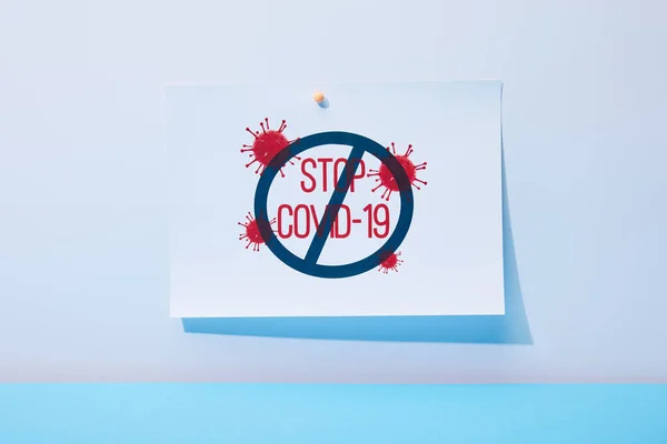 Papier avec lettrage stop covid-19 sur fond bleu — Photo de stock
