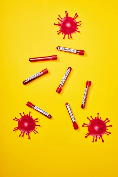 Top view of test tubes with coronavirus test lettering and drawn virus on yellow — Stock Photo