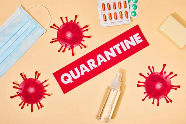 Top view of paper with quarantine lettering near drawn virus, hand sanitizer, soap bar and medical mask on beige — Stock Photo