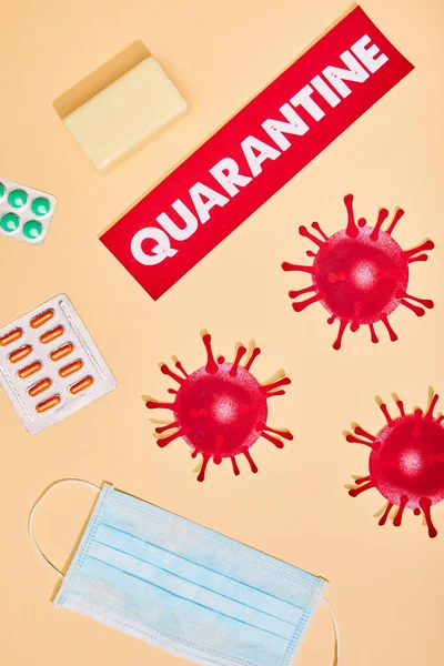 Top view of paper with quarantine lettering near drawn virus, soap bar and medical mask  on beige — Stock Photo