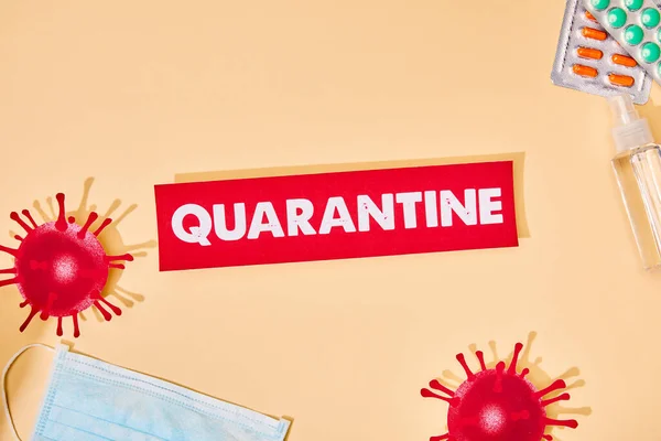 Top view of paper with quarantine lettering near drawn virus, soap bar, pills and hand sanitizer on beige — Stock Photo