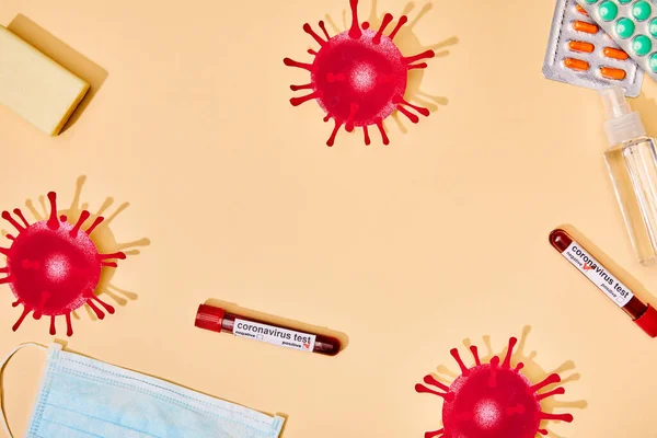 Top view of drawn virus near test tubes, soap bar, medical mask, pills and hand sanitizer on beige — Stock Photo