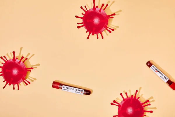 Vista dall'alto del virus disegnato vicino alle provette con scritta coronavirus su beige — Foto stock