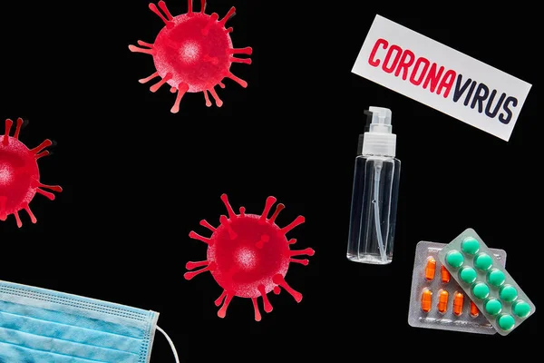 Vista dall'alto di carta con scritte coronavirus vicino a maschera medica, pillole e disinfettante per le mani isolato su nero — Foto stock