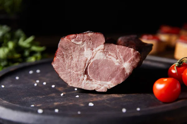 Close up view of tasty ham on board with scattered salt and cherry tomatoes — Stock Photo