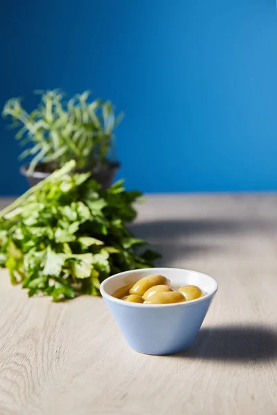 Foco seletivo de salsa e azeitonas na tigela na mesa de madeira no fundo azul — Fotografia de Stock