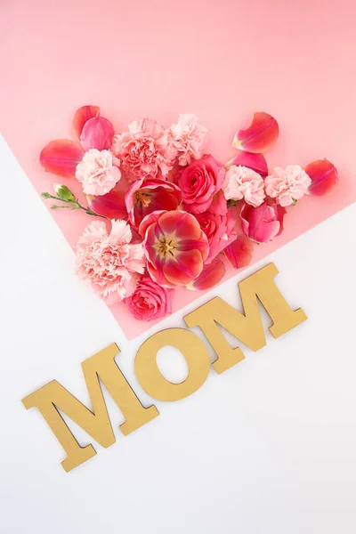 Vista superior de flores y letras de mamá sobre fondo rosa y blanco - foto de stock