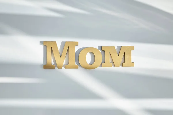 Vista superior de las letras de mamá sobre fondo blanco con sombras - foto de stock